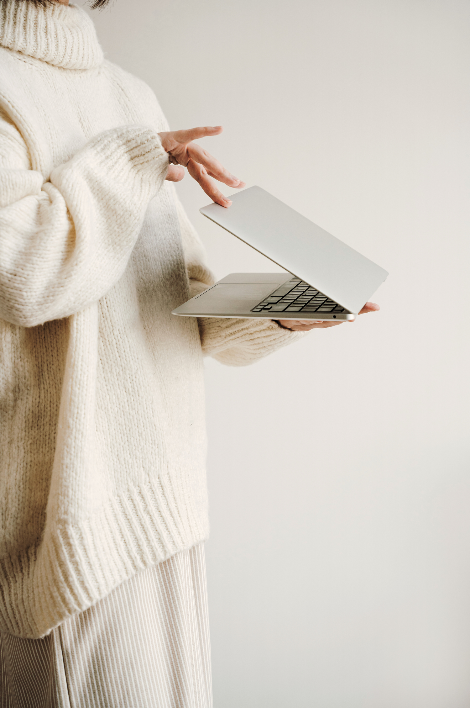 Model in an all white outfit closing a laptop